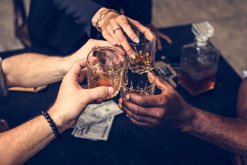 Friends drinking whiskey and cheering glasses together